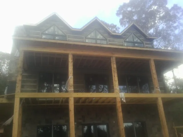 Dormers and porch framing on a large log home under construction — Roof Coating work by our crew in Carthage